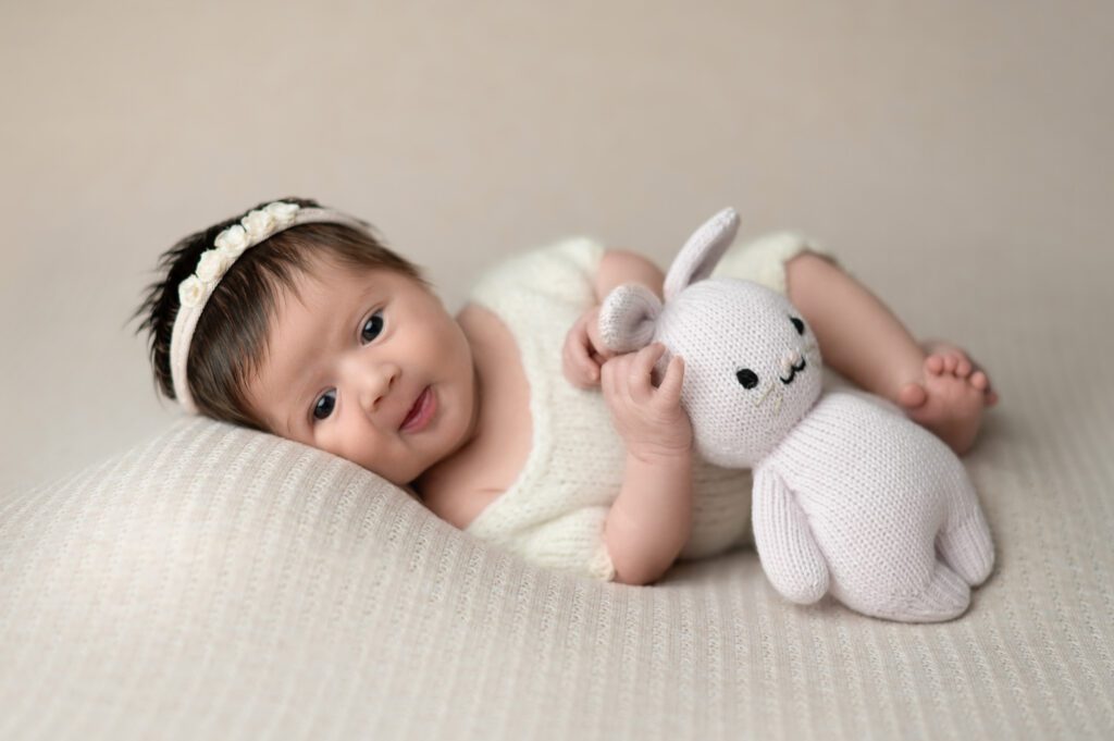 a baby holding a bunny on w creem blanket