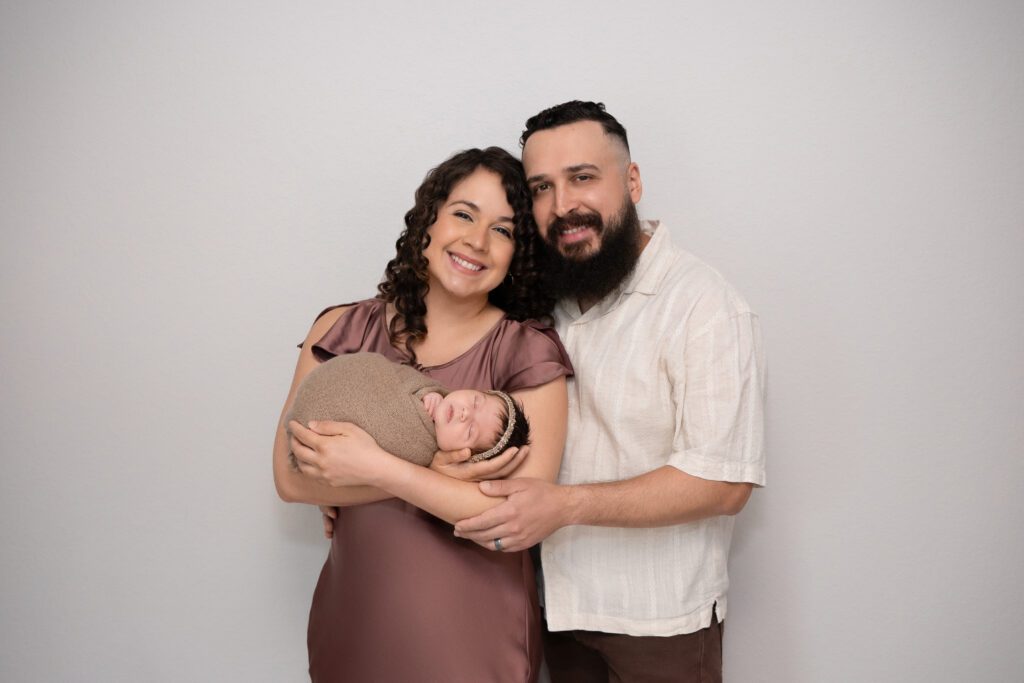 A mom and father holding their baby in a family photoshoot