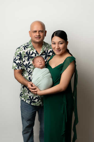 Parents holding newborn baby during family portrait session in studio setting.